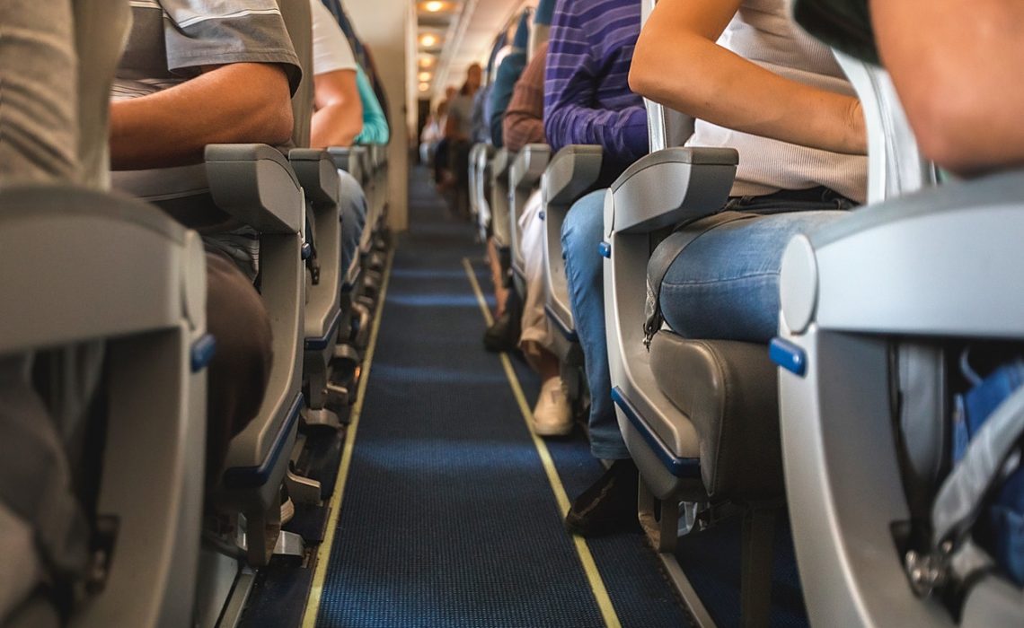 cabin of airplane with unrecognizable passengers on seats waiting to take off.