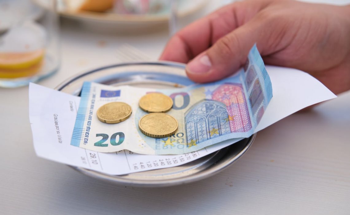 Hand bringing back the metal bill tray with the change at the bar table.