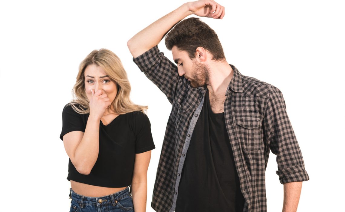 The man smells armpits near the woman on the white background